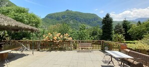 Une terrasse extérieure avec des tables et des chaises, une clôture en bois et une vue sur les montagnes.