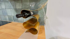 Una bottiglia di vino su un supporto curvo in metallo, con uno sfondo di piastrelle.