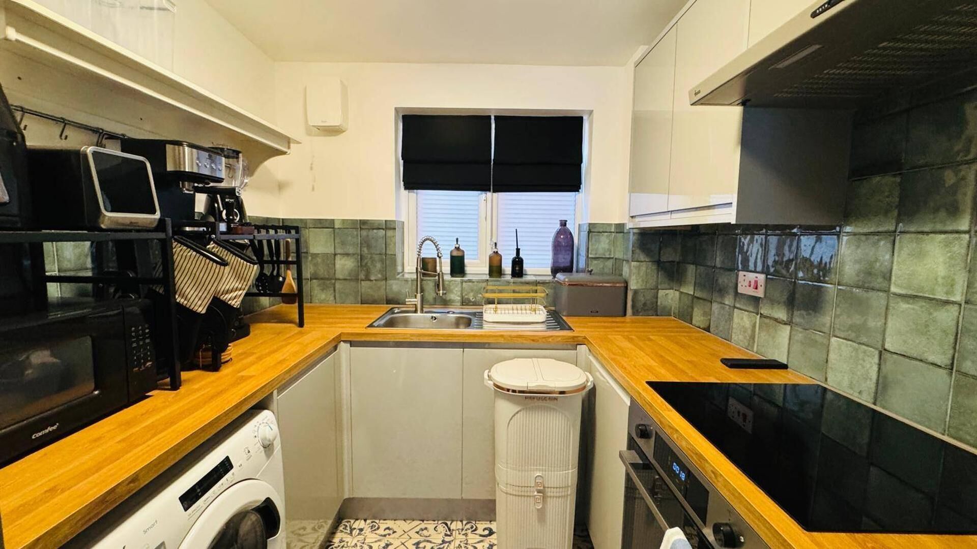 Cocina compacta con lavadora, microondas y fregadero.