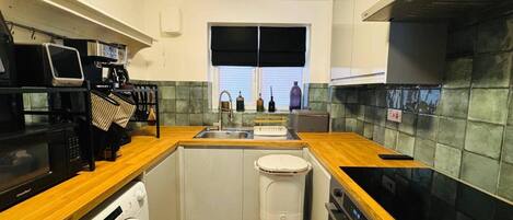 Cocina compacta con lavadora, microondas y fregadero.
