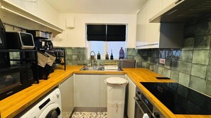 Una cucina compatta con lavatrice, forno a microonde e lavello.