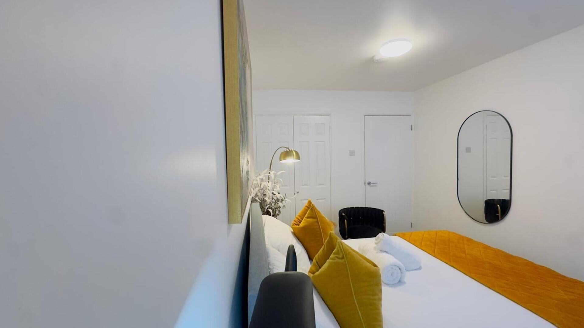 Ett hotellrum med en säng, ett skrivbord, en stol, en spegel och en dörr.