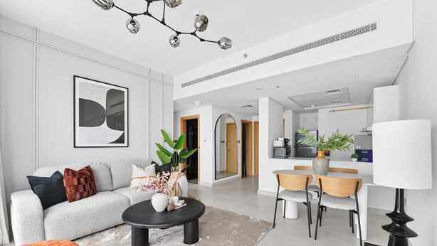 A modern living room with a sofa, coffee table, and dining area. - Silkhaus Premium 2BR in Reem Island in Radiant Bay (Abu Dhabi)