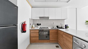 A modern kitchen with white cabinets, a stainless steel refrigerator, a built-in oven, and a dishwasher. - Silkhaus Premium 2BR in Reem Island in Radiant Bay (Abu Dhabi)