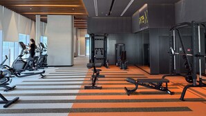 A modern gym with treadmills, weight machines, and a large mirror. - Silkhaus Premium 2BR in Reem Island in Radiant Bay (Abu Dhabi)