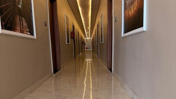 A long, well-lit hallway with marble floors and framed artwork on the walls. - The Classic Crown (Ayodhya)