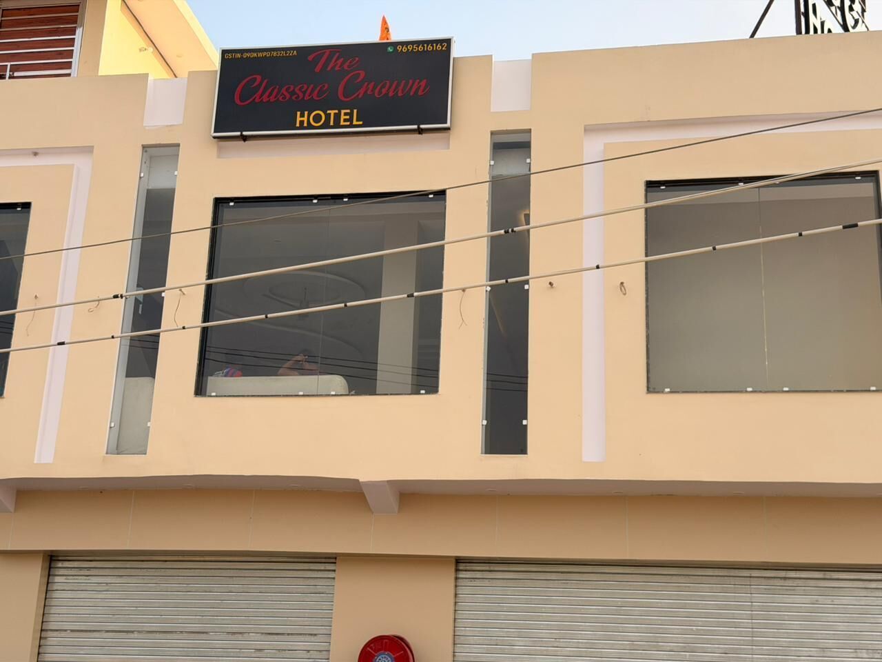 Un letrero de hotel con el nombre 'The Classic Crown Hotel' y un número de contacto.