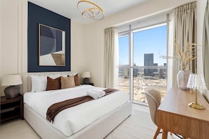 A hotel room with a large bed, a desk, a view of the city, and a modern abstract painting on the wall. - Silkhaus Vacation Homes Premium 2bdr With Maid Room in Radiant Viewz (Abu Dhabi)
