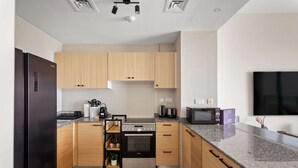 Una cucina moderna con mobili in legno, forno integrato, microonde e un grande televisore a schermo piatto montato a parete.