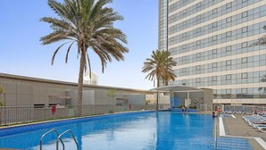 Una piscina con palme, una zona coperta e un edificio alto sullo sfondo.