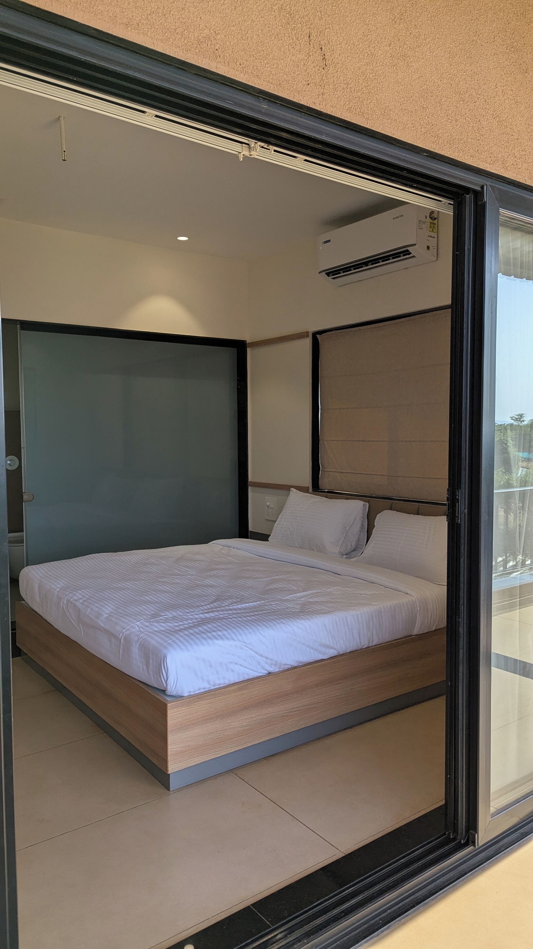 A modern bedroom with a large bed, a sliding door, and an air conditioning unit.
