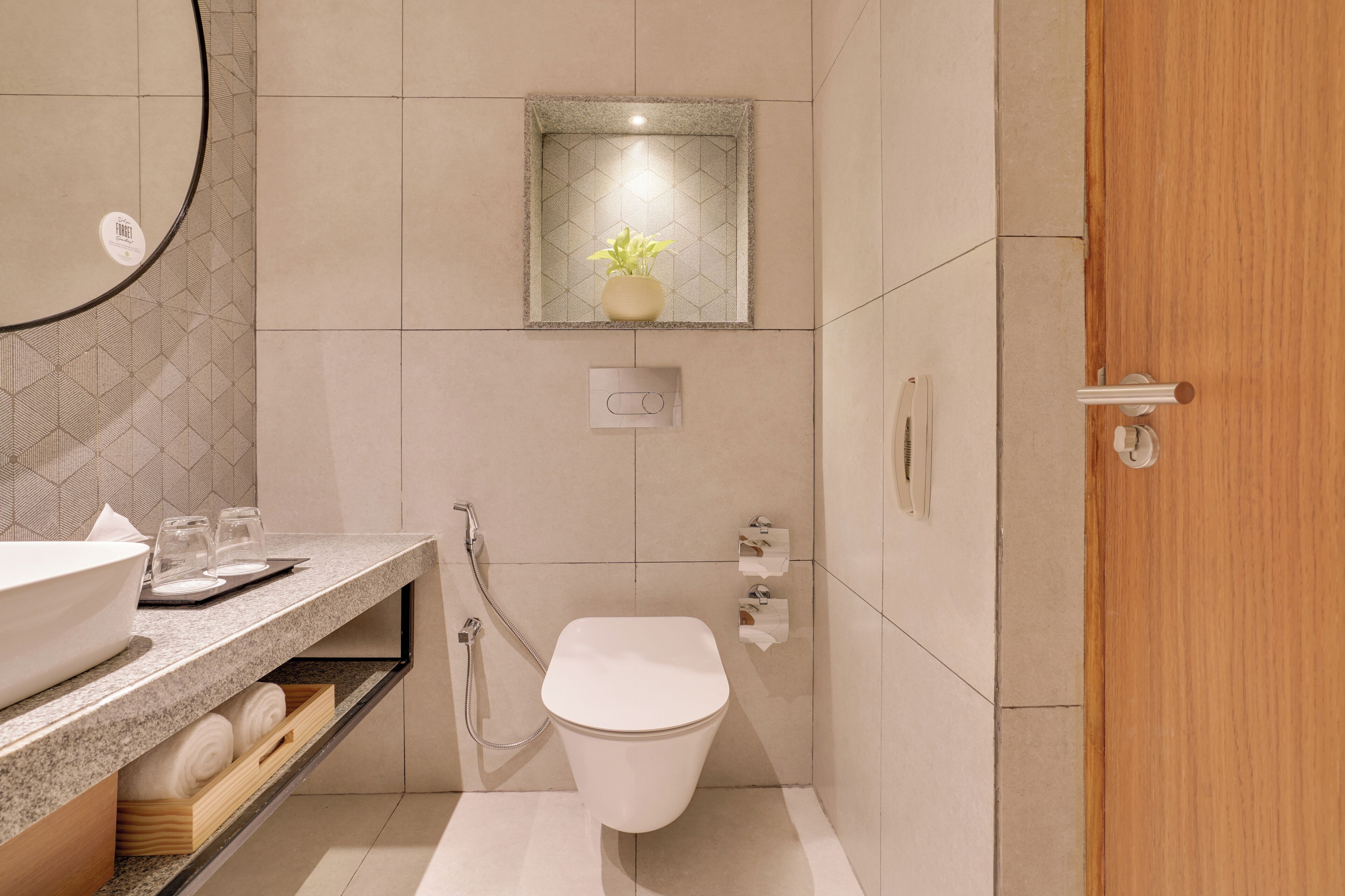 A modern bathroom with a sink, toilet, and a small shelf with towels.