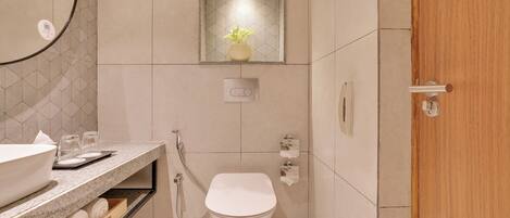 A modern bathroom with a sink, toilet, and a small shelf with towels.