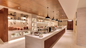 A modern kitchen with a long island, wooden ceiling, pendant lighting, and built-in shelves. - Lemon Tree Premier Biratnagar Nepal (Biratnagar)