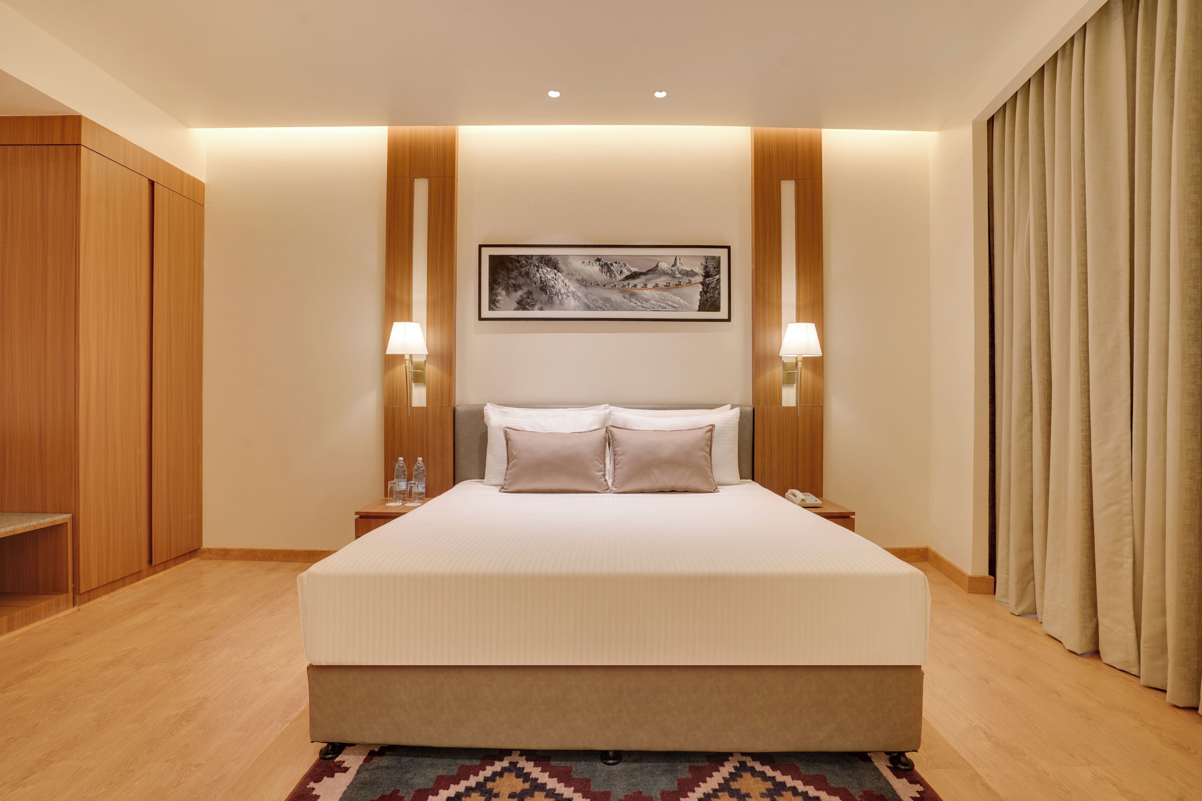 Ein Hotelzimmer mit einem großen Bett, einem Holzschrank, zwei Nachttischlampen und einem gerahmten Bild an der Wand.