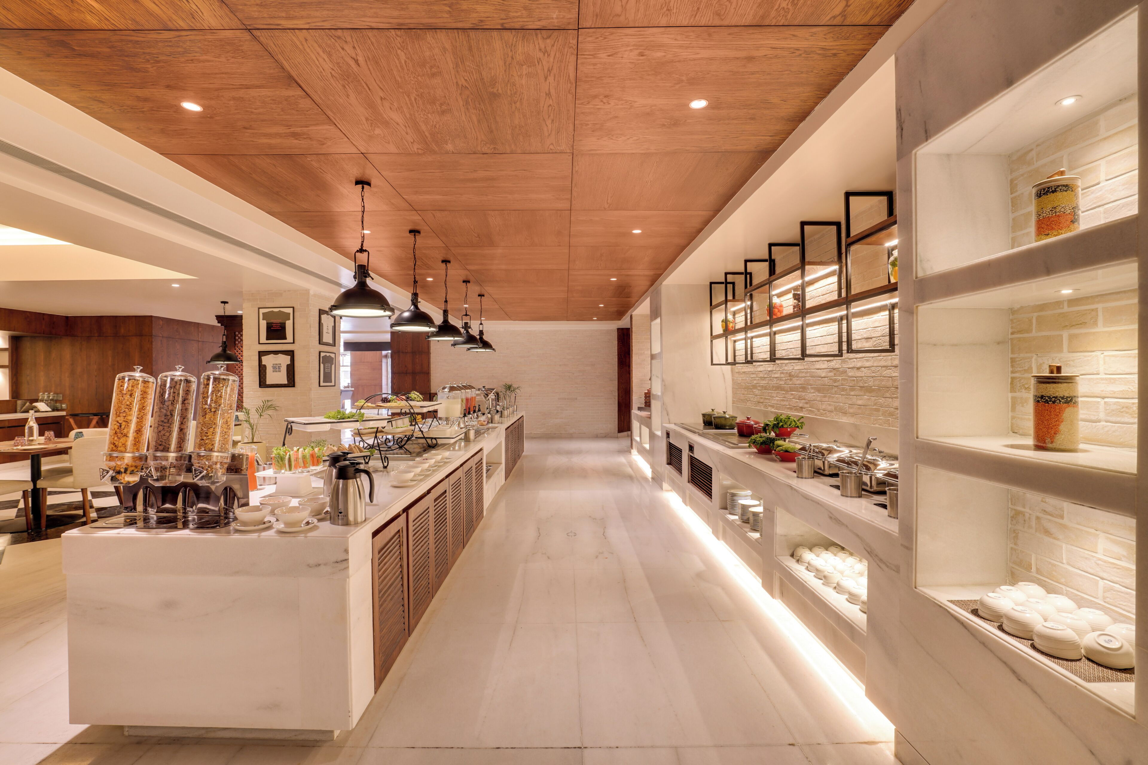 A modern hotel lobby with a marble floor, wooden ceiling, and a long counter with various amenities.