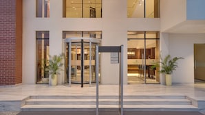 A modern building entrance with a revolving door, potted plants, and a visible interior with seating. - Lemon Tree Premier Biratnagar Nepal (Biratnagar)