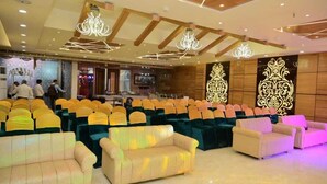 A spacious hall with rows of chairs and sofas, a bar area, and a chandelier. - Hotel Gurveer Royal (Lucknow)