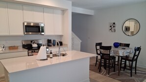 Una cocina moderna con armarios blancos, un microondas de acero inoxidable y una isla central con pileta.