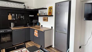 Een moderne keuken met een zwart fornuis, een spoelbak en een roestvrijstalen koelkast.
