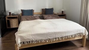 Een slaapkamer met een bed, twee nachtkastjes, een plank boven het bed en een houten vloer.