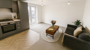 Ett modernt kök med en inbyggd ugn och en matplats med en soffa och ett soffbord.