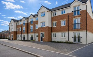 A modern residential building with multiple floors, large windows, and a paved driveway. - Cosy one bed flat near Liverpool Anfield Stadium(LFC),great view and parkings (Liverpool)