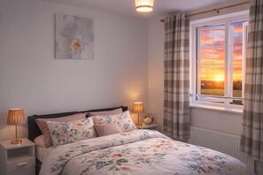 A bedroom with a bed, two bedside tables, a nightstand, a window with curtains, and a wall-mounted light fixture. - Cosy one bed flat near Liverpool Anfield Stadium(LFC),great view and parkings (Liverpool)