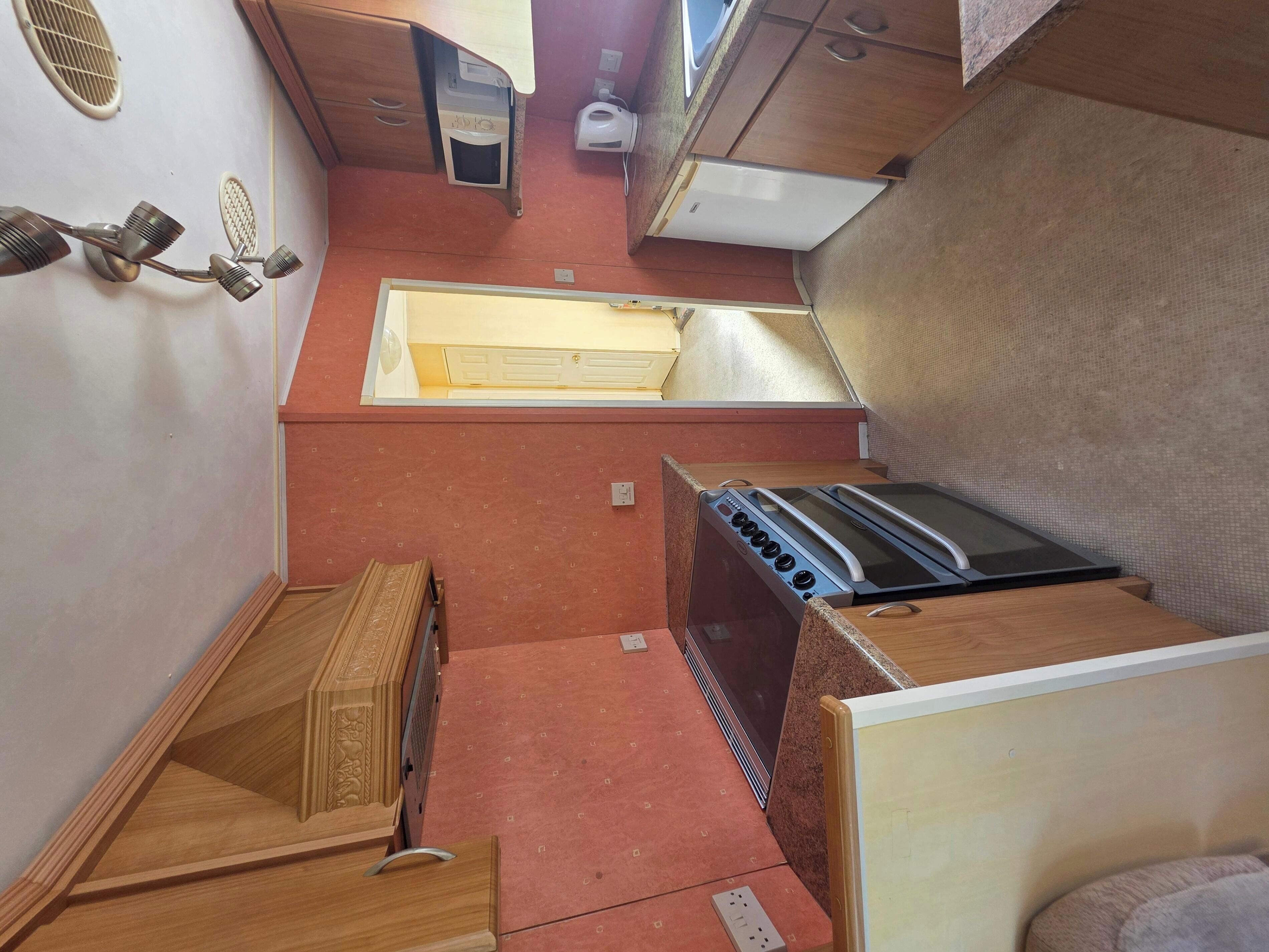 A compact kitchen with a stove, oven, microwave, and a sink.
