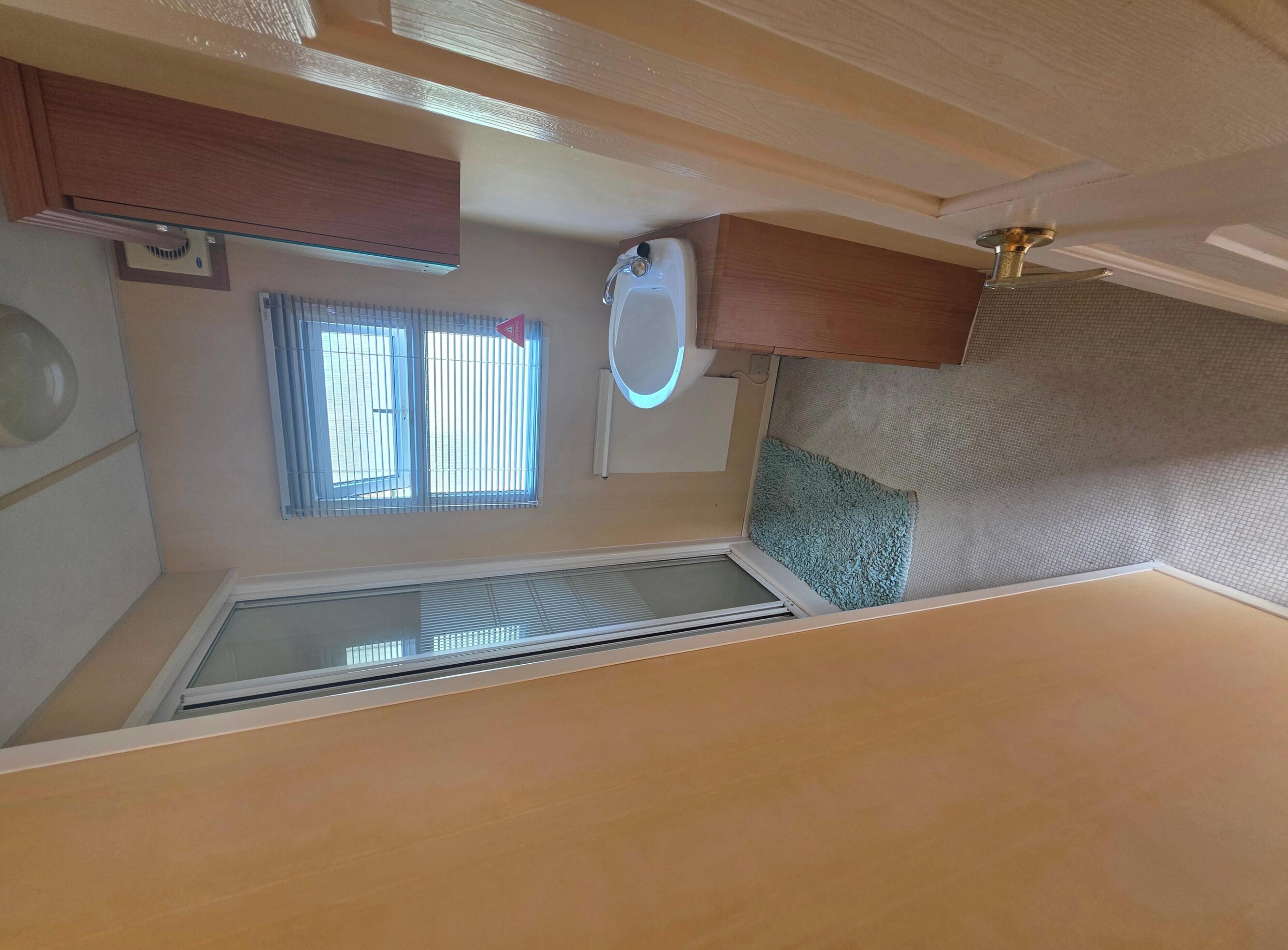 A bathroom with a toilet, sink, and window.