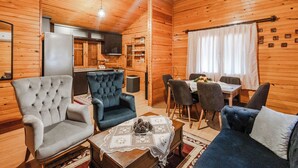Interior acogedor de una cabaña de madera con comedor, cocina y dos zonas de estar.