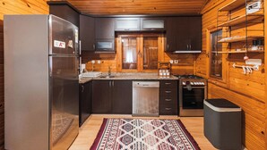 Una cocina compacta con armarios de madera, un refrigerador de acero inoxidable, un lavavajillas y una estufa.