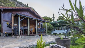 Una casa de madera con porche, piso de piedra y mobiliario exterior.