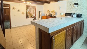 A kitchen with a wooden ceiling, a tiled floor, and a built-in island with a microwave and coffee maker. - Tropical duplex by the sea (direct private access) (Libreville)