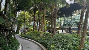 A curved pathway surrounded by lush greenery and tall trees. - BKK Oasis Stylish & Cozy Condo Near MRT 200m (Bangkok)