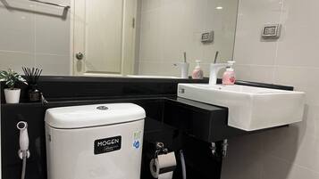 A bathroom with a white toilet, black sink, and a mirror above the sink.