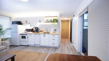 Eine moderne Küche mit weißen Schränken, einem Backofen und einer Kaffeemaschine.