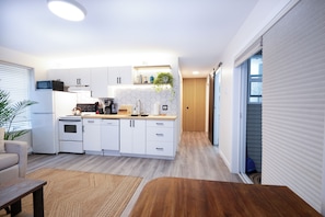 A modern kitchen with white cabinets, a built-in oven, and a coffee machine.