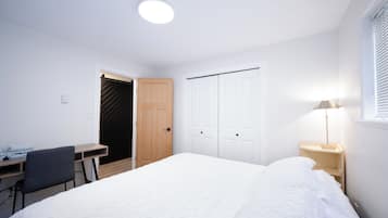 Ein Schlafzimmer mit einem Bett, einem Schreibtisch, einem Stuhl, einem Kleiderschrank und einer Nachttischlampe.