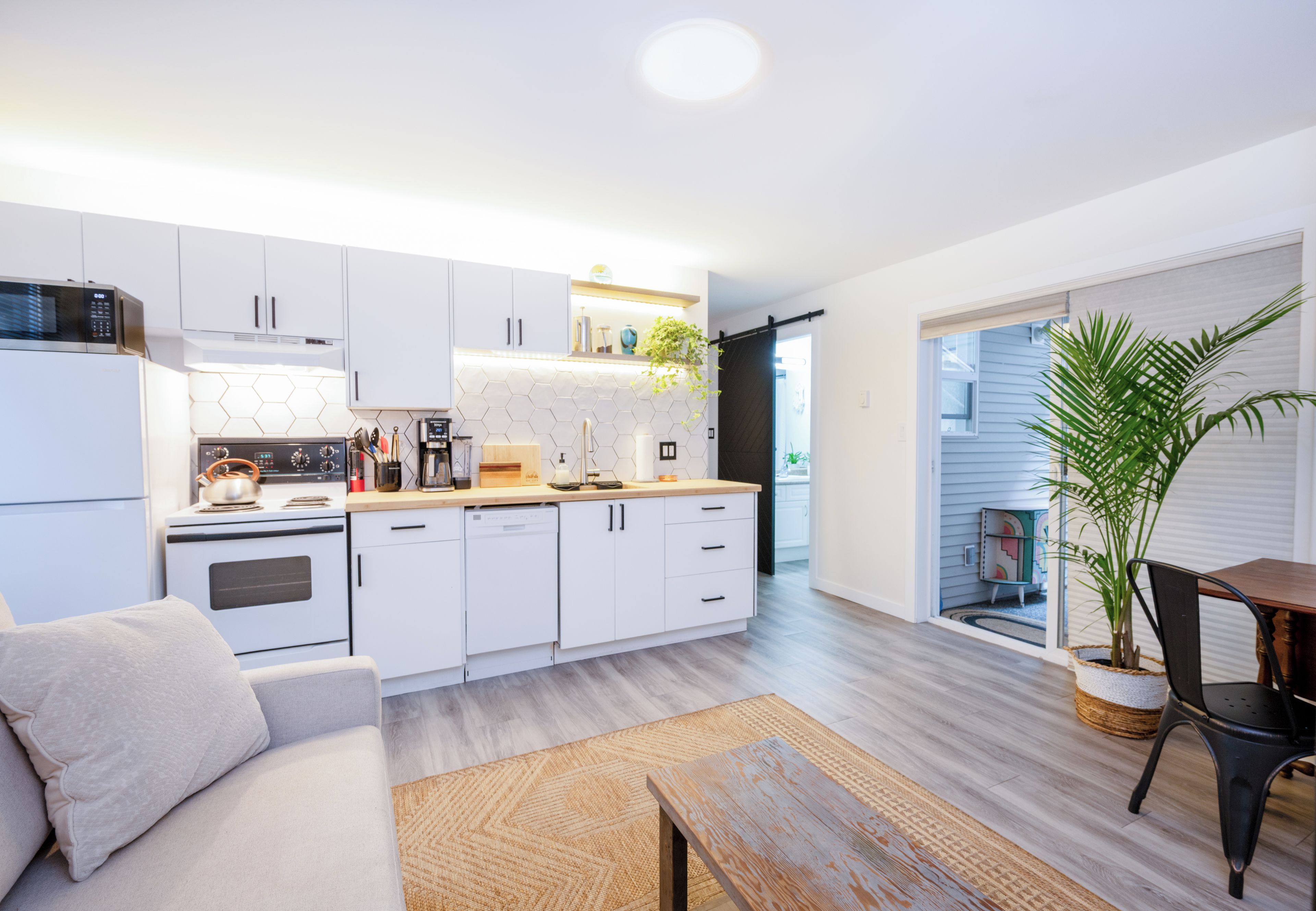 A modern kitchen with white cabinets, a built-in oven, and a coffee machine.