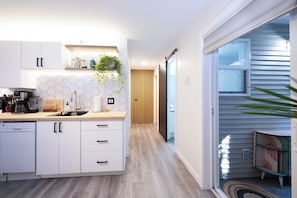 A modern kitchen with white cabinets, a coffee machine, and a wooden countertop.