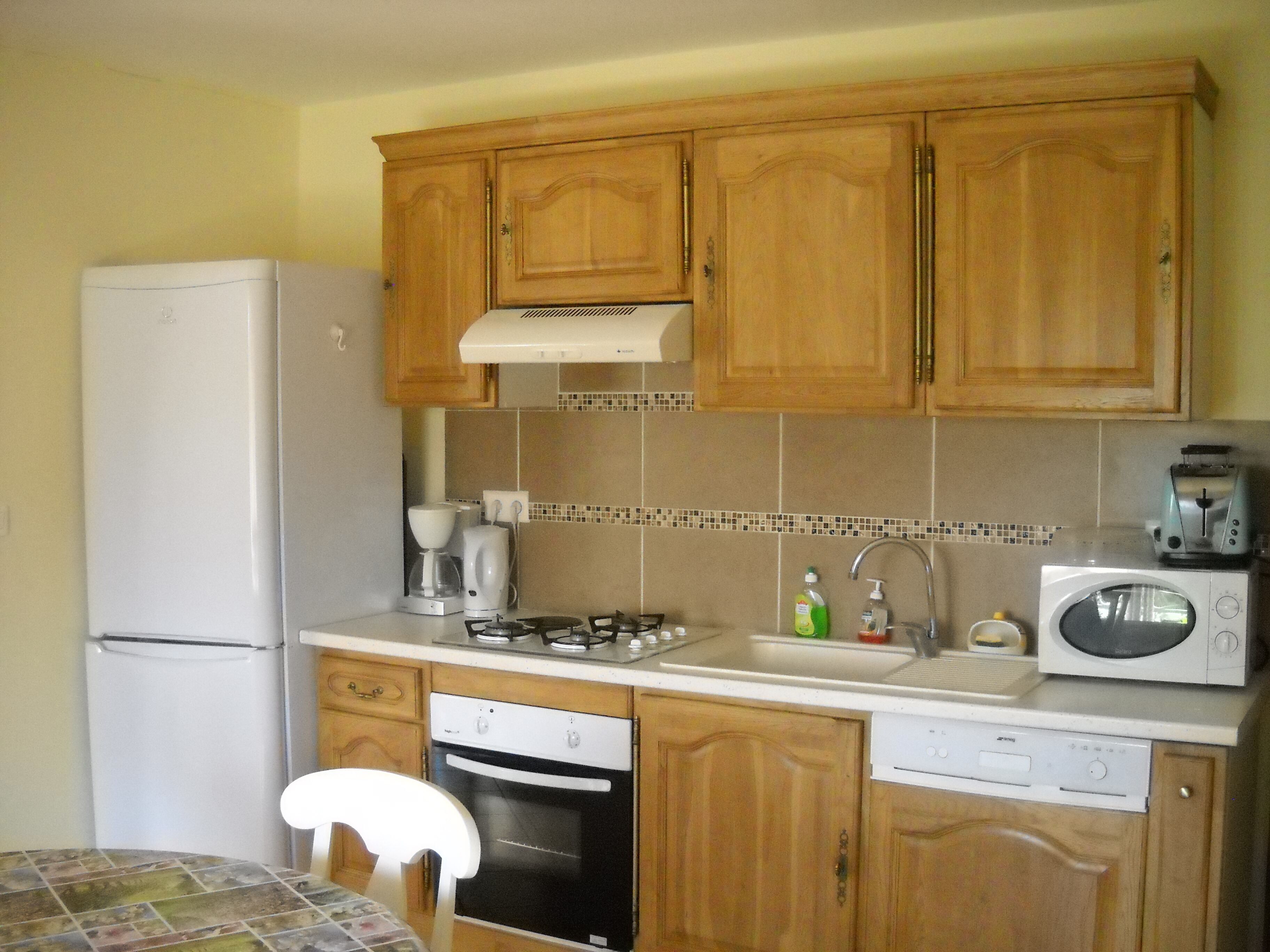 Une cuisine compacte avec des meubles en bois, un réfrigérateur blanc, une cuisinière, un four à micro-ondes et un lave-vaisselle.