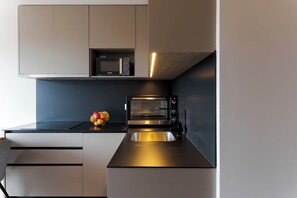 Eine moderne Küche mit integriertem Mikrowellenherd, Backofen und Spüle aus Edelstahl.