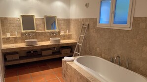 Een badkamer met twee wastafels, een badkuip en een raam.