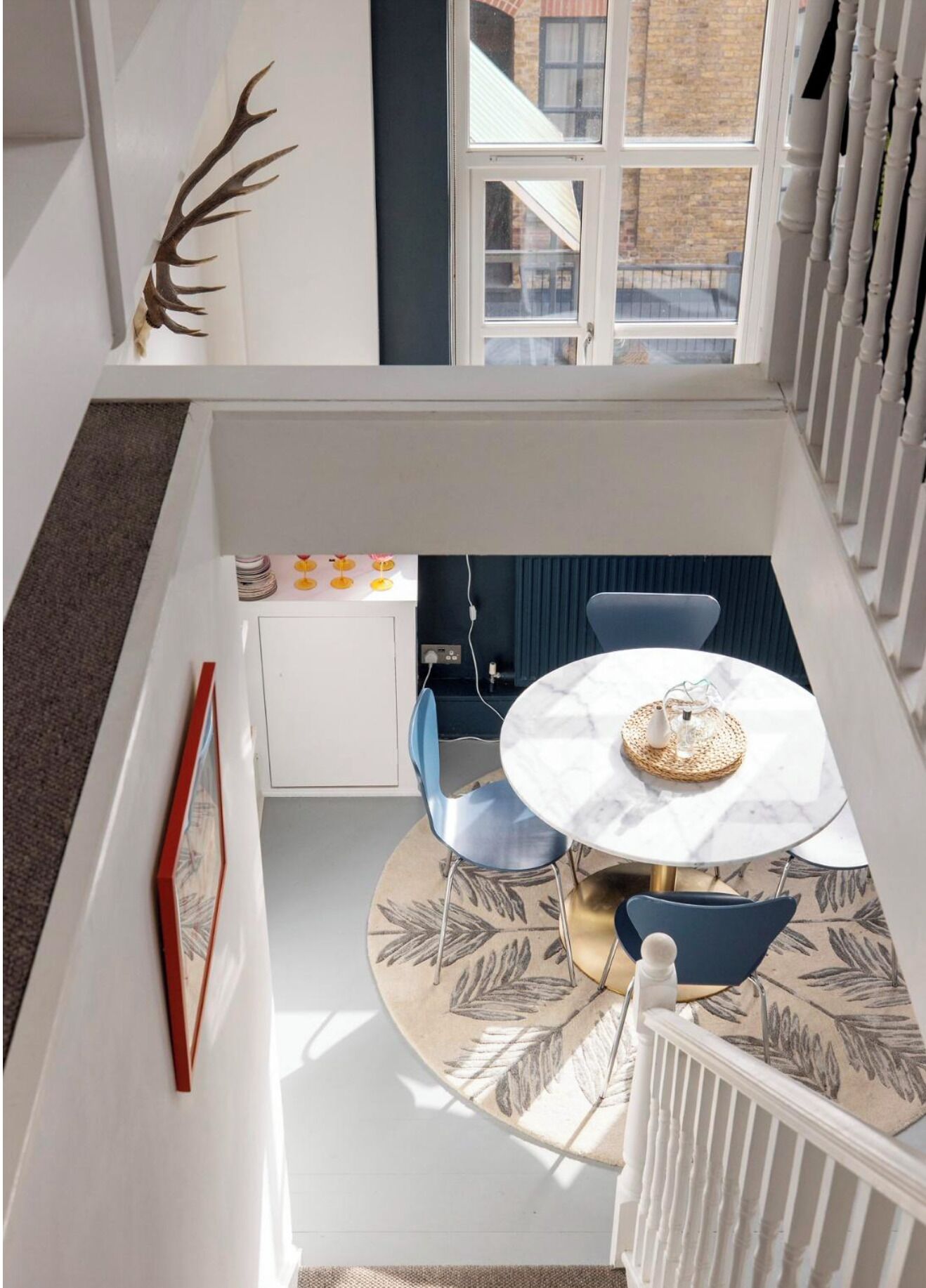 Un coin repas comprenant une table ronde, des chaises, un élément décoratif mural et une vue sur l’extérieur.