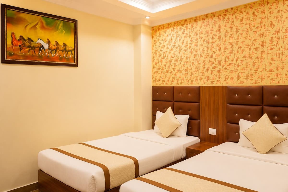 A hotel room with two beds, a headboard, and a painting on the wall.