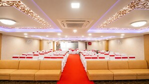 A conference room with rows of white chairs, a red carpet aisle, and beige sofas. - Hotel Hyfa Continental (Lucknow)