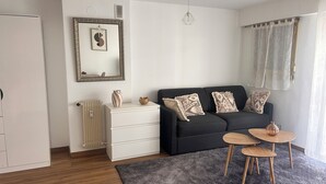 Ein modernes Wohnzimmer mit einem schwarzen Sofa, einer weißen Kommode und einem grauen Teppich.
