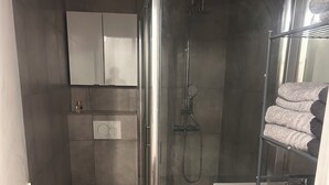 Ein kleines Badezimmer mit Toilette, Dusche und Waschmaschine.
