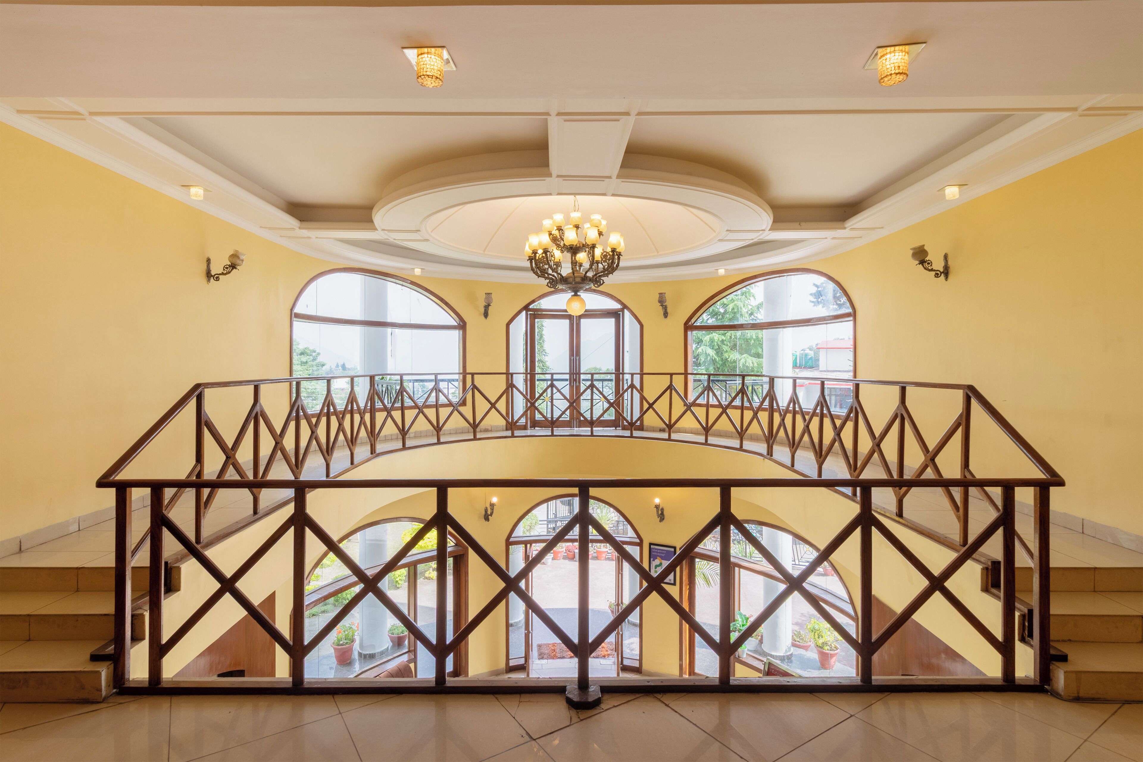 A spacious interior with a central balcony, large arched windows, and a chandelier.